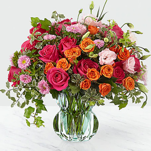 Pink and Orange Assored Flowers in a Vase with Greens